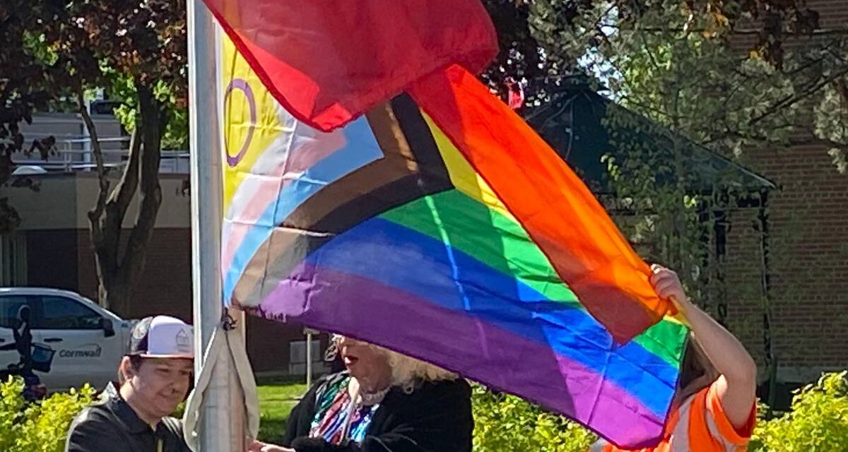 Three people raise a 2SLGBTQIA_ flag on the International Day against Transphobia, Homophobia and Biphobia in Cornwall, Ontario on Wednesday, May 17, 2023.