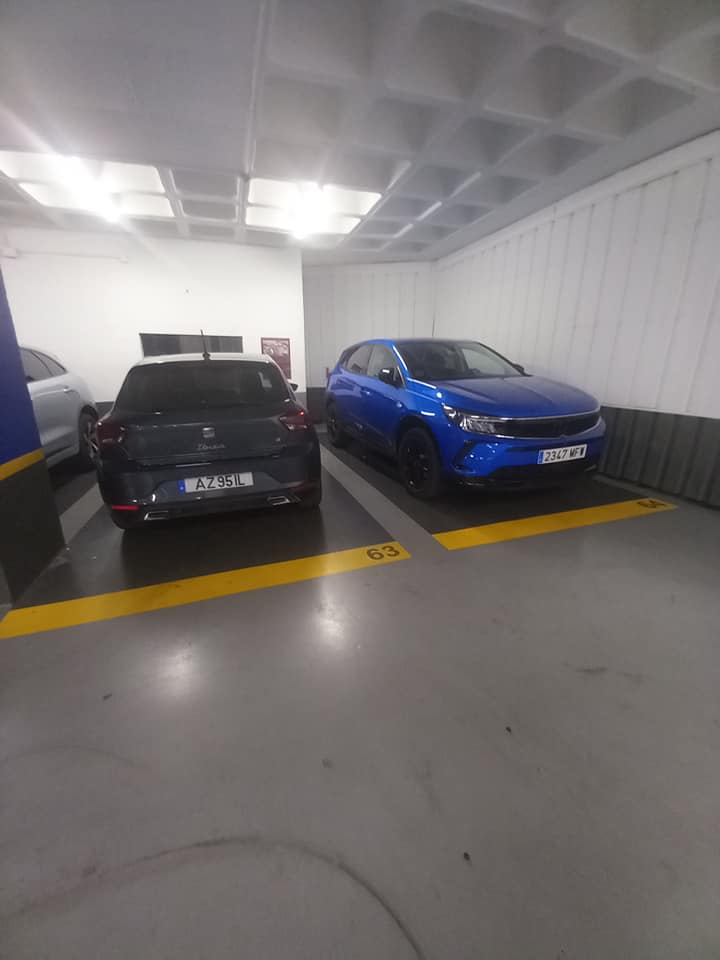 Two cars parked in a parking garage in parking space #63 in Seville, Spain.