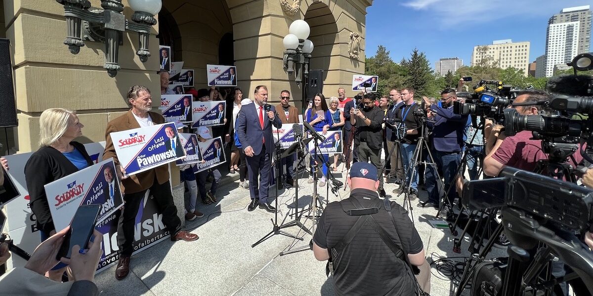 Street preacher Artur Pawlowski flanked by his supporters and facing the media on the steps of the Legislature in Edmonton.