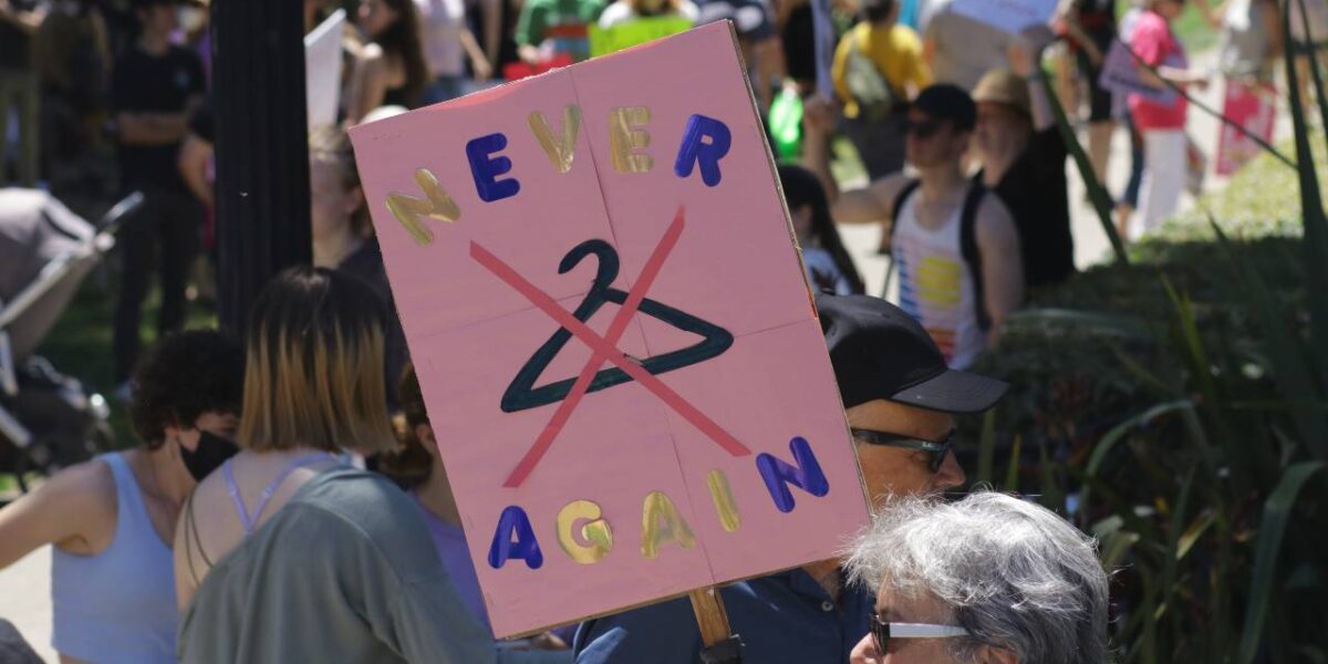 A sign opposing restrictions to abortions, featuring a coat hanger with a red X over it with the words "never again."