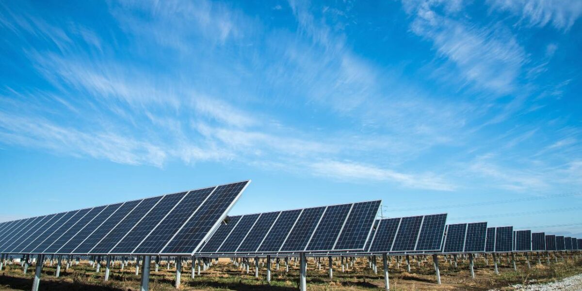 A field of solar panels beneath a blue sky.