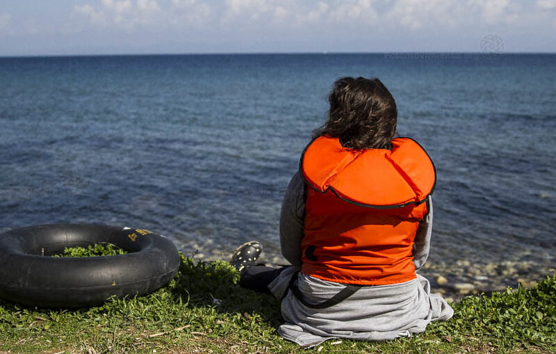 A person wearing a life jacket typically worn by migrant refugees and migrant travellers.