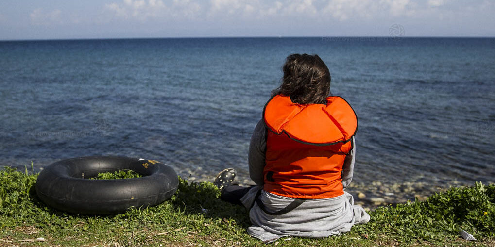 A person wearing a life jacket typically worn by migrant refugees and migrant travellers.