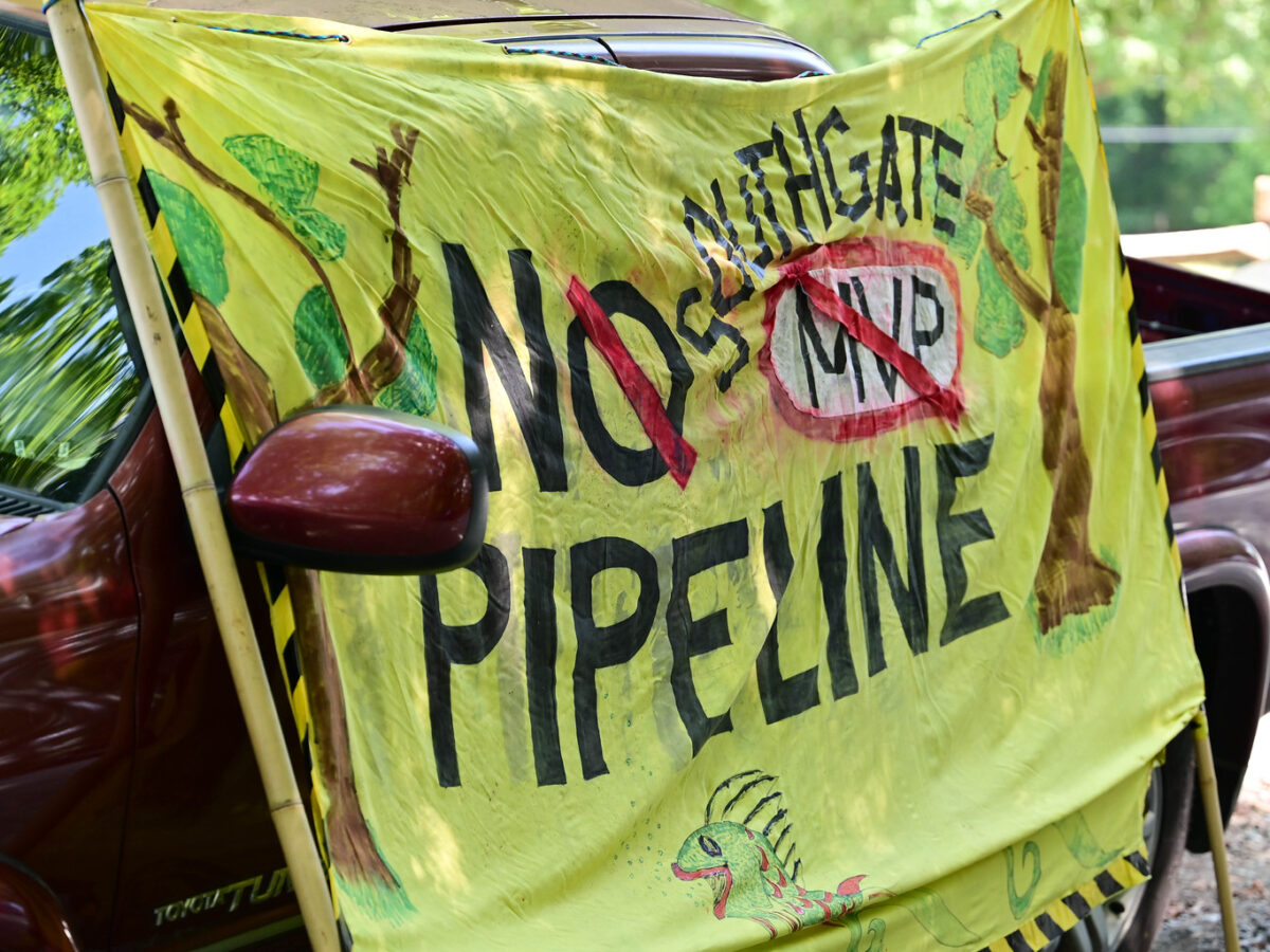 A sign expressing opposition to the Mountain Valley Pipeline leans against the side of a car.