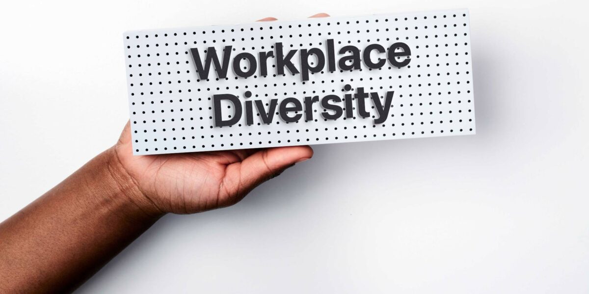 A hand holding up a sign reading workplace diversity.