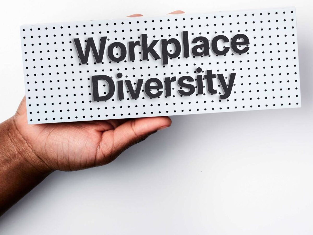 A hand holding up a sign reading workplace diversity.