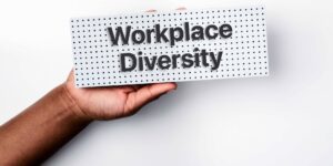 A hand holding up a sign reading workplace diversity.