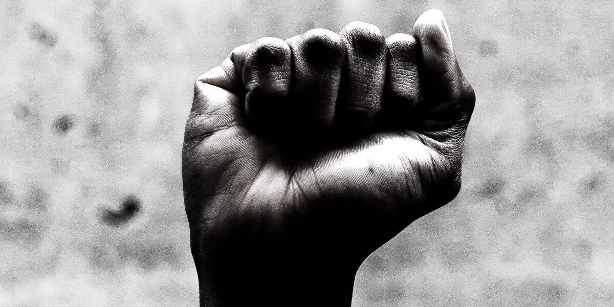 A person's raised fist symbolizes solidarity with the struggle for racial justice on Juneteenth.