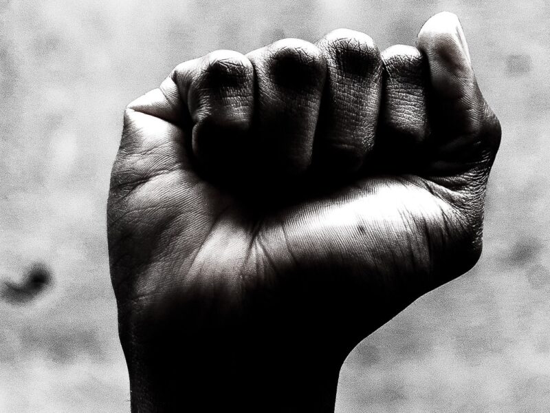 A person's raised fist symbolizes solidarity with the struggle for racial justice on Juneteenth.