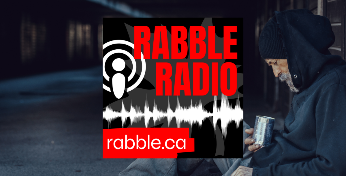 A homeless person sitting down on the sidewalk, rabble radio logo.