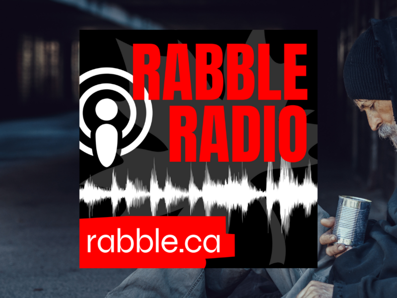 A homeless person sitting down on the sidewalk, rabble radio logo.