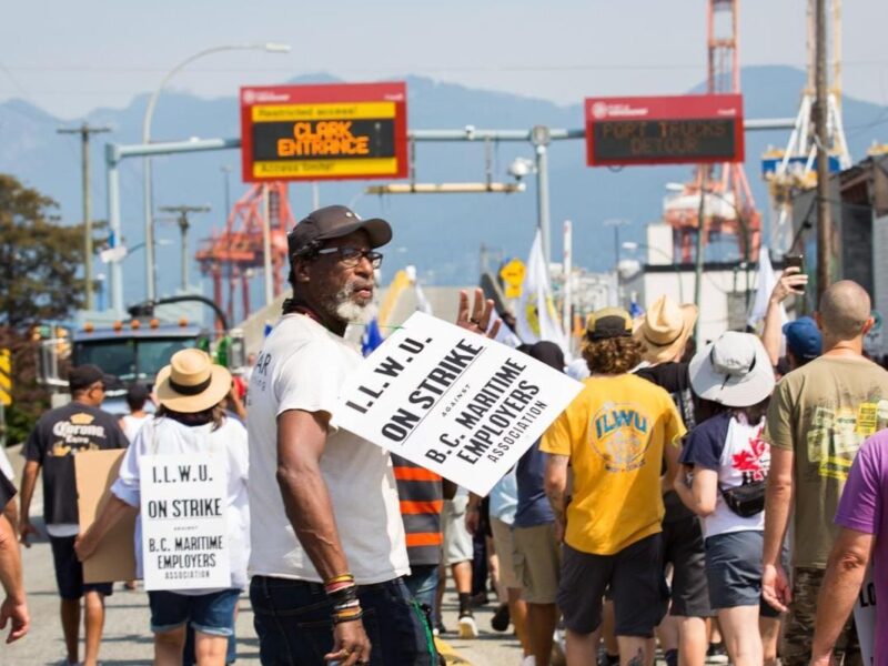 Crowd of port strikers marching down highway.