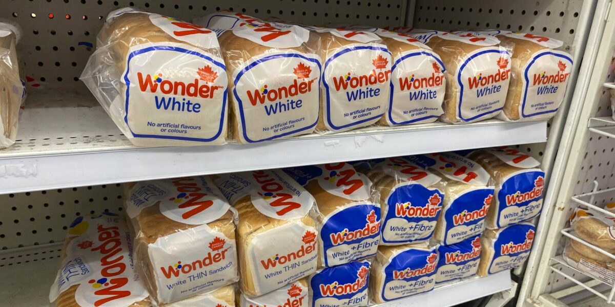 Packages of bread on a grocery store shelf.