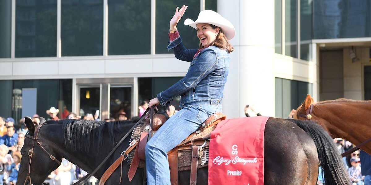 Photo of Alberta Premier Danielle Smith wearing cowboy gear, riding on horse