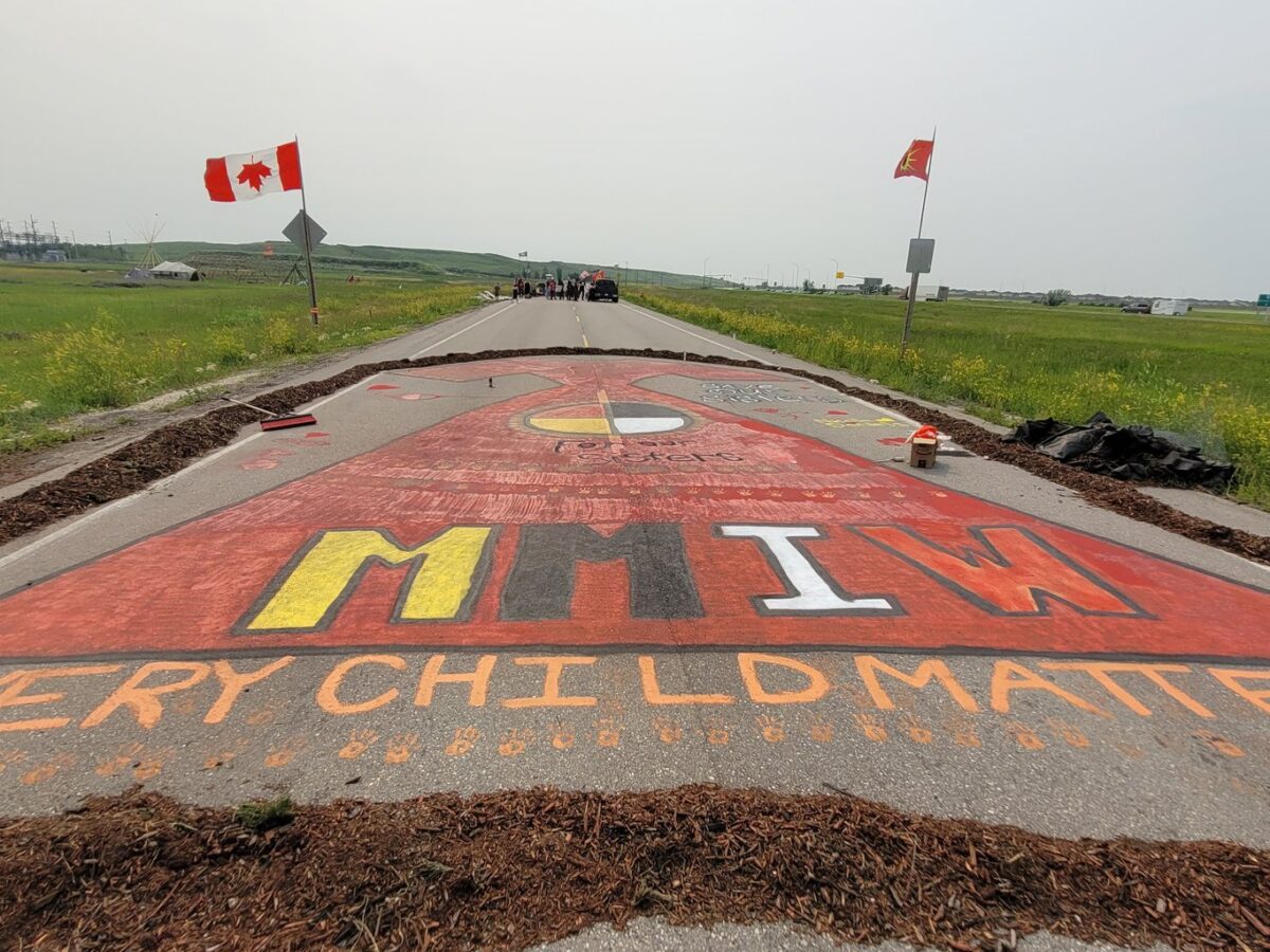Image of the blockade at the Brady Landfill. A road is painted with the words "every child matters" and "MMIGW."