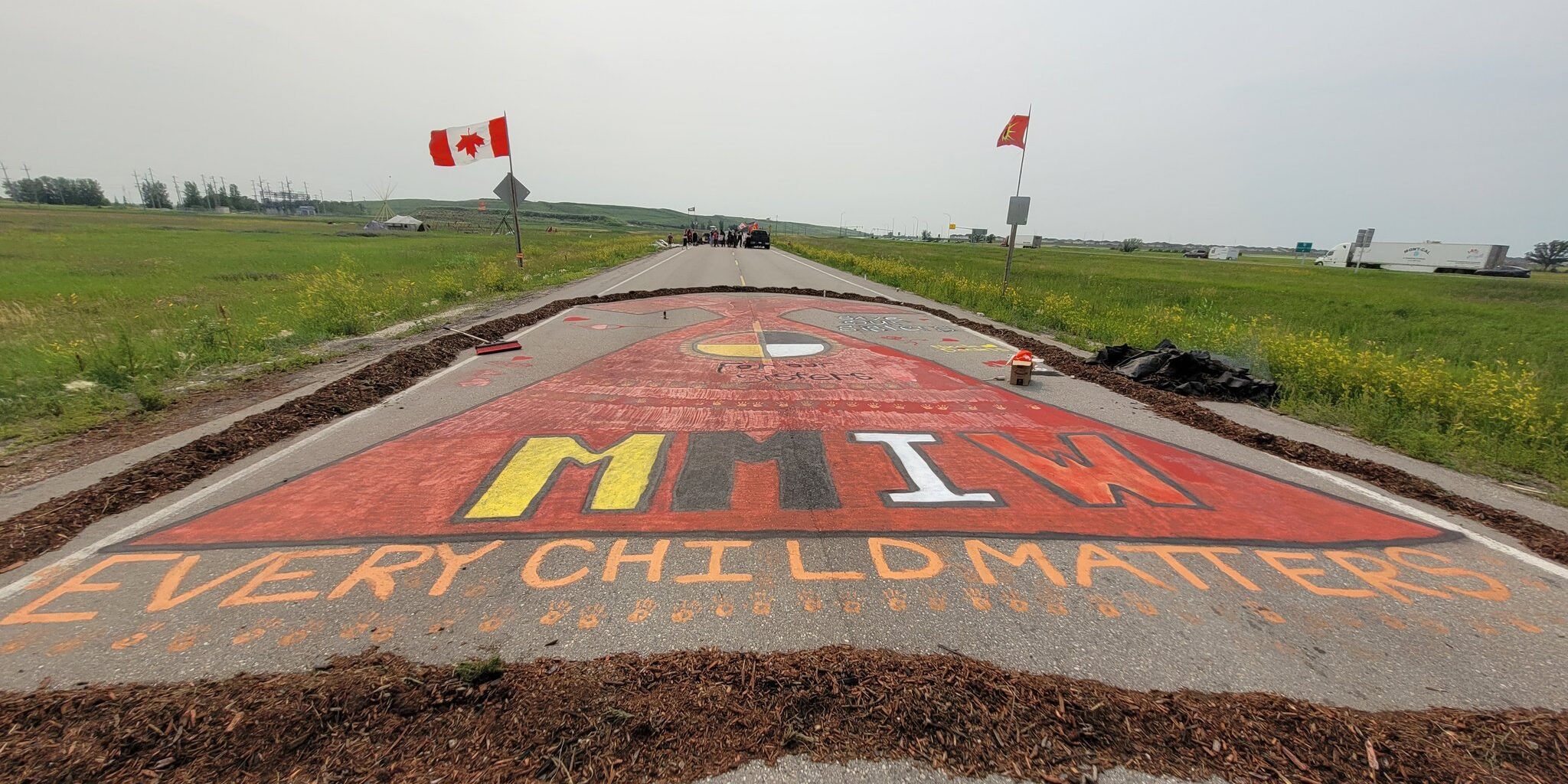 Image of the blockade at the Brady Landfill. A road is painted with the words "every child matters" and "MMIGW."