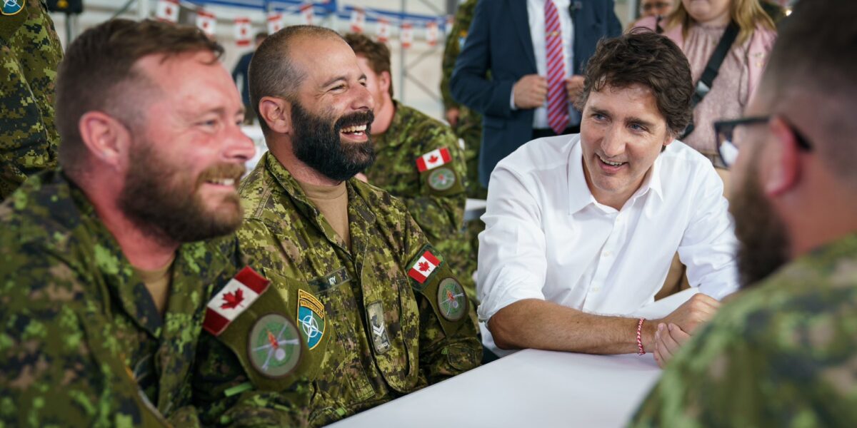 Prime Minister Justin Trudeau sitting with Canadian Forces members at Camp Ādaži in Latvia.