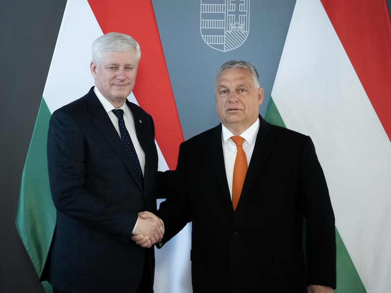 Stephen Harper and Viktor Orbán shaking hands in front of Hungarian flag.