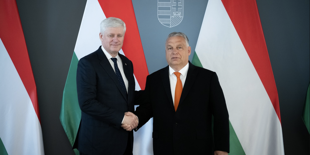 Stephen Harper and Viktor Orbán shaking hands in front of Hungarian flag.