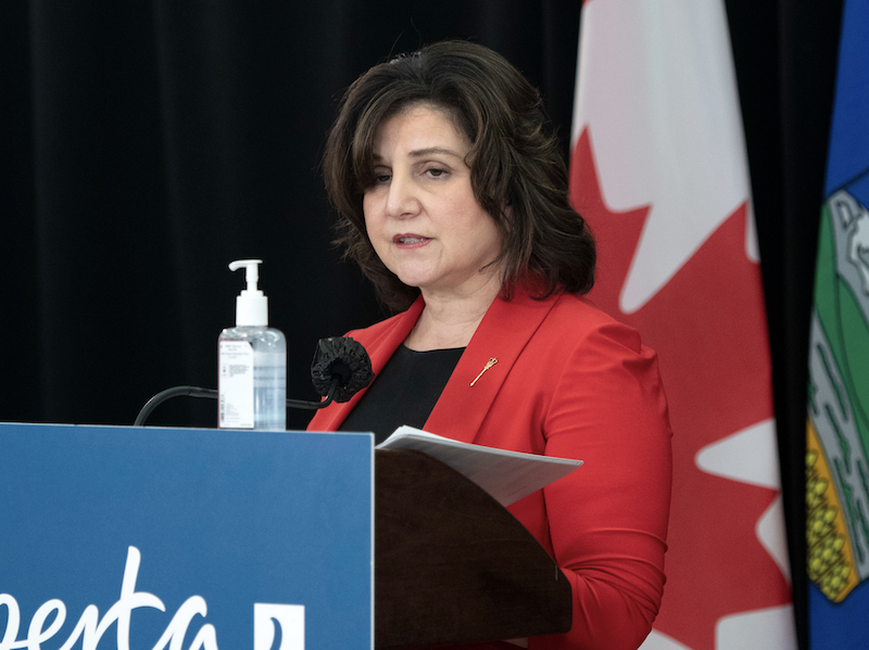 Health Minister Adriana LaGrange in 2021, then the education minister, behind podium.