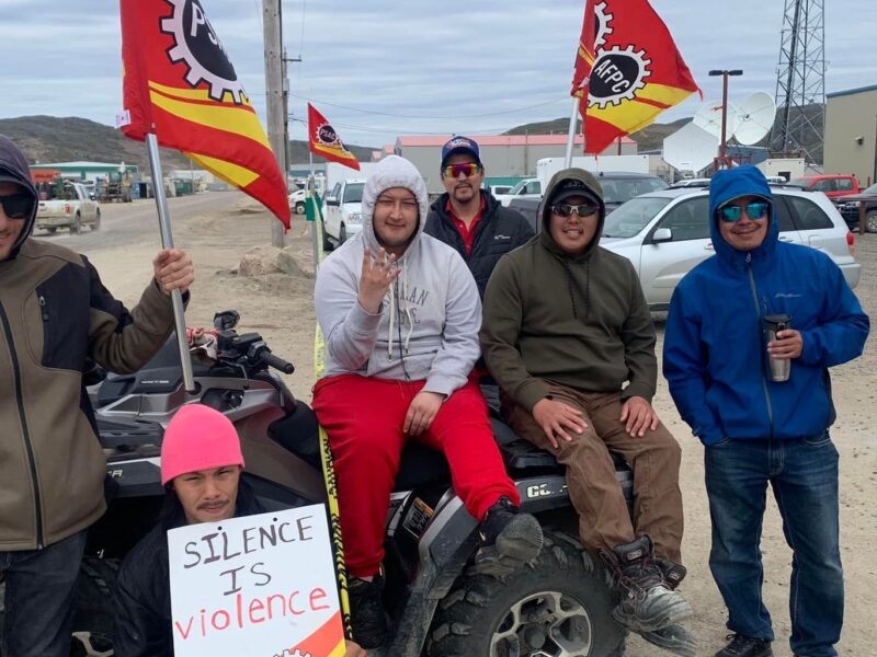 A group of striking workers pose for a photo on the picket line