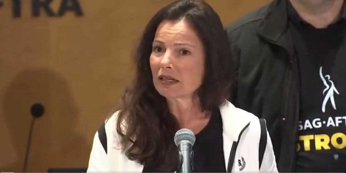 SAG-AFTRA President Fran Drescher speaking to the media from behind a microphone.