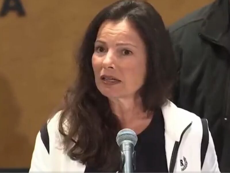 SAG-AFTRA President Fran Drescher speaking to the media from behind a microphone.