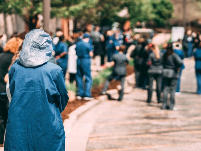 An image of healthcare workers in scrubs protesting amidst the health crisis.