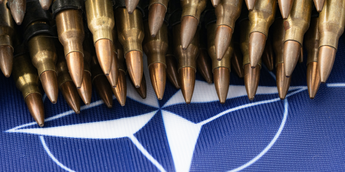 A pile of bullets sits atop the NATO flag.