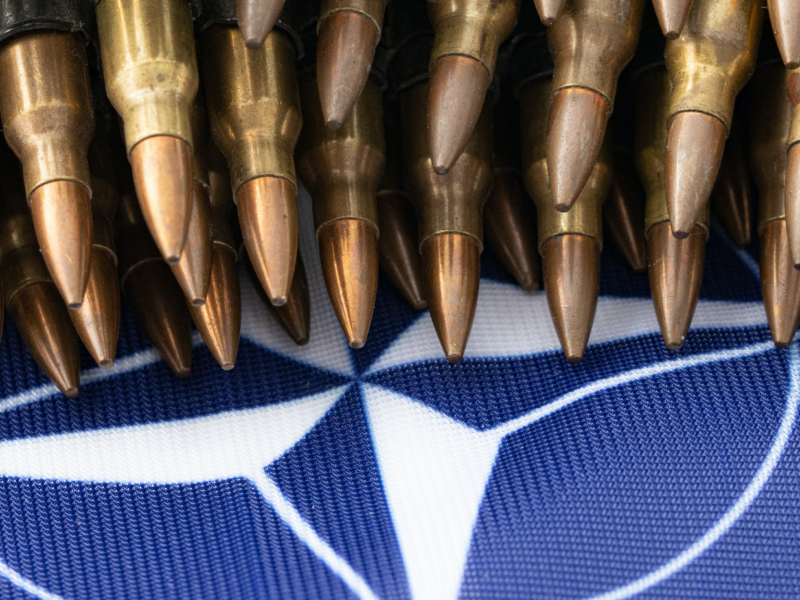 A pile of bullets sits atop the NATO flag.