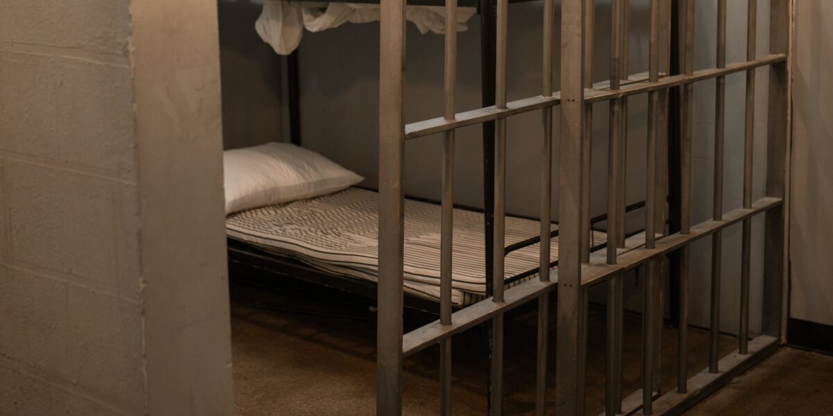 A prison cell partially open with a bunk bed in view