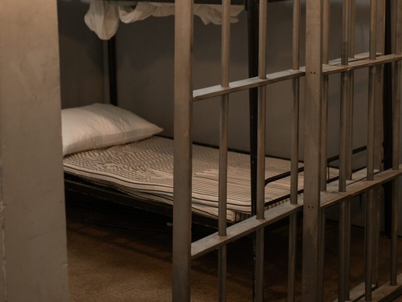 A prison cell partially open with a bunk bed in view