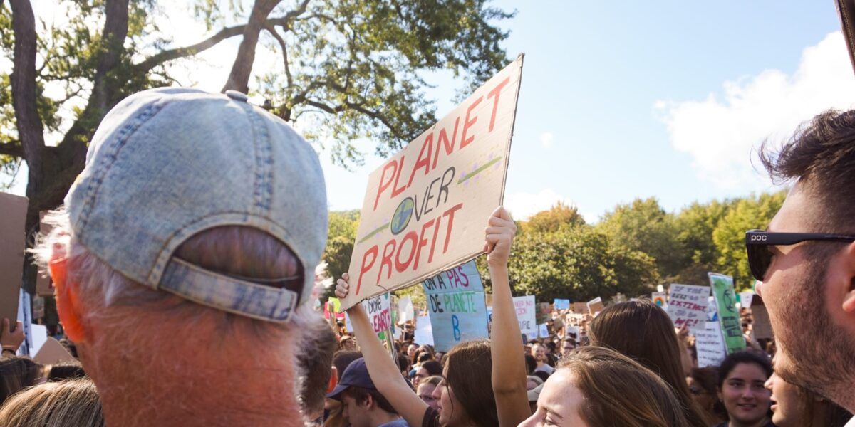 Protestors, holding sign that says "people over profit."