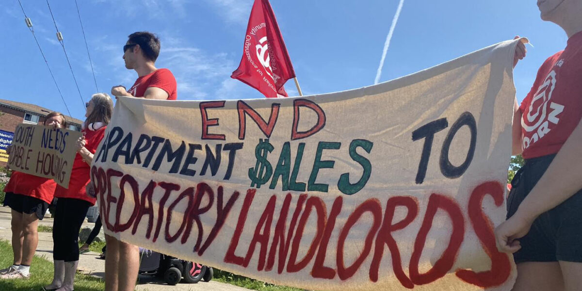 Tenants hold signs protesting predatory landlord practices.