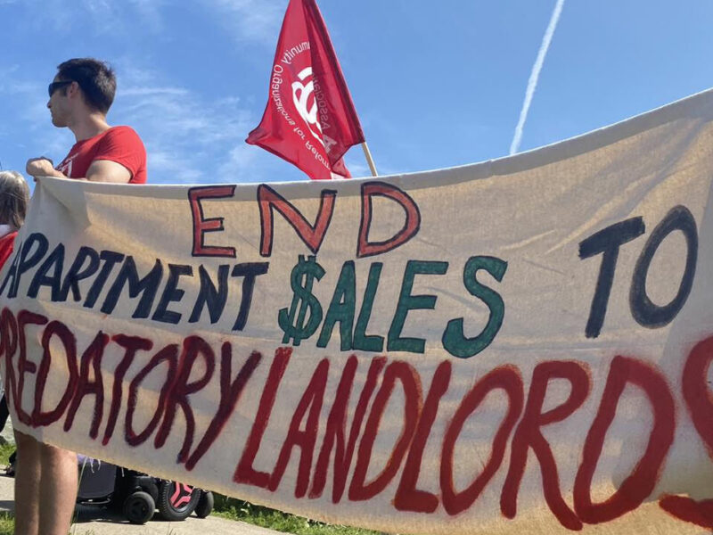 Tenants hold signs protesting predatory landlord practices.