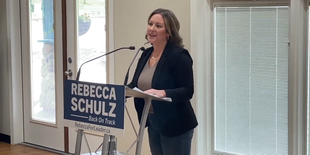 Rebecca Schulz standing at a podium speaking into a mic