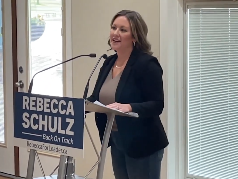 Rebecca Schulz standing at a podium speaking into a mic