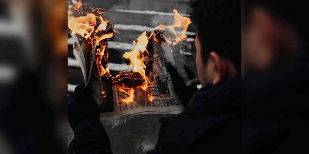 A man reads a burning newspaper.