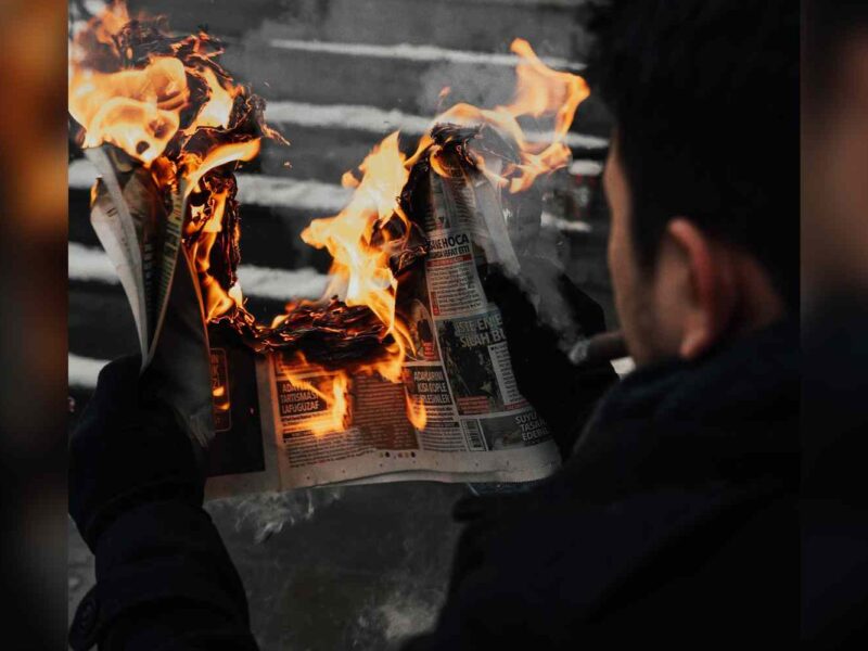 A man reads a burning newspaper.