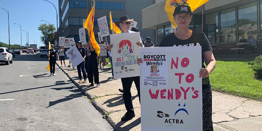 ACTRA members protesting outside of a Wendy's holding signs.