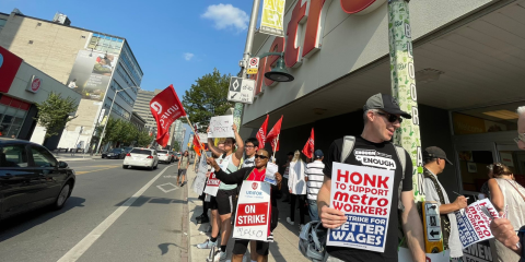 An image of striking metro workers on the picket line with signs. Metro workers are striking for better wages.