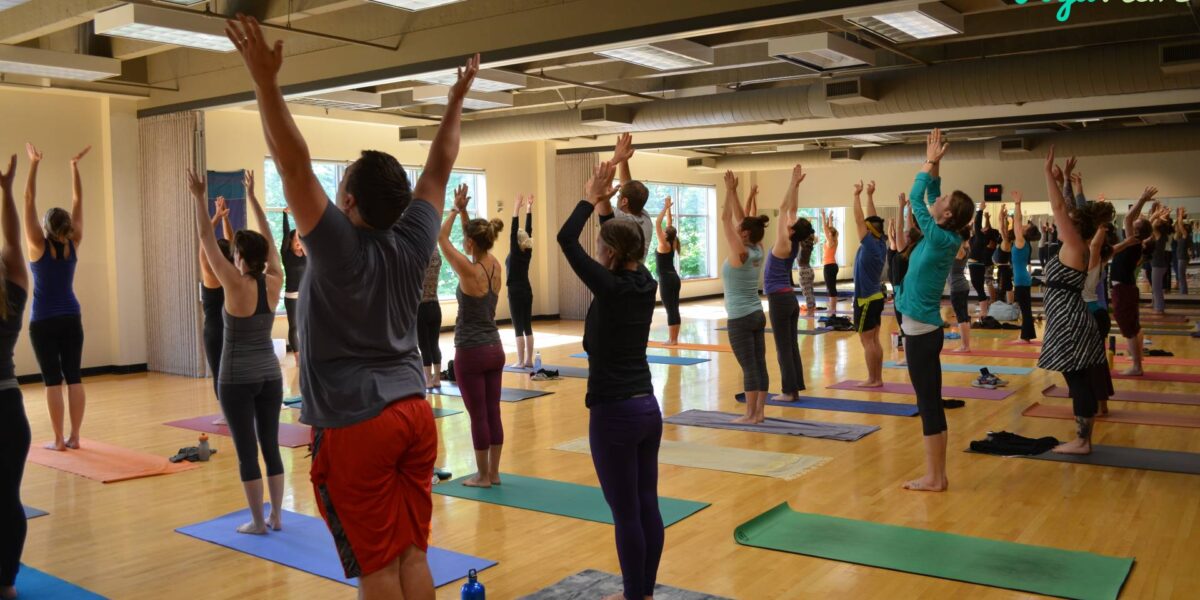 A yoga class stretching on a wood floor.