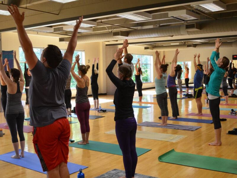 A yoga class stretching on a wood floor.