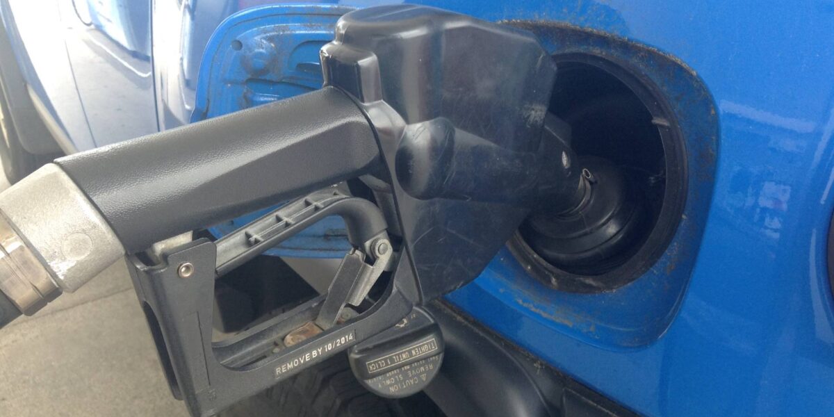 A truck being filled with gas from a pump.