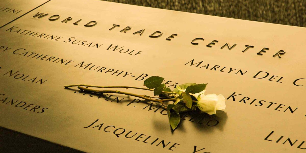 A photo of the World Trade Centre memorial with a white rose laying on it.