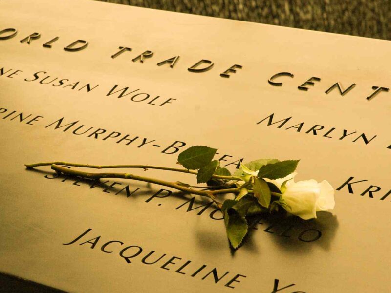 A photo of the World Trade Centre memorial with a white rose laying on it.