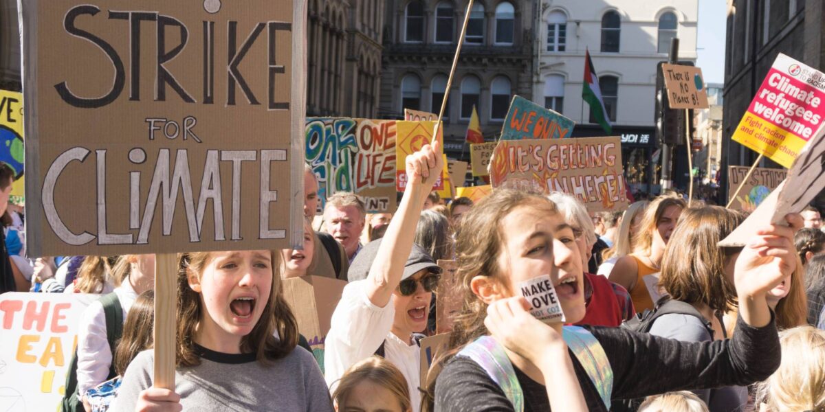 Youth hold up signs calling for an end to greenhouse gas emissions during a climate strike in 2019.