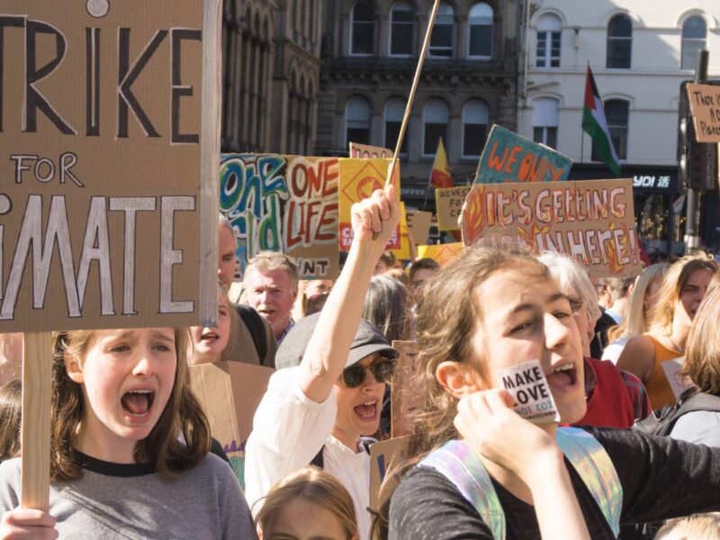 Youth hold up signs calling for an end to greenhouse gas emissions during a climate strike in 2019.