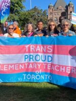 Teachers holding a flag that says "trans proud elementary teachers of Toronto."