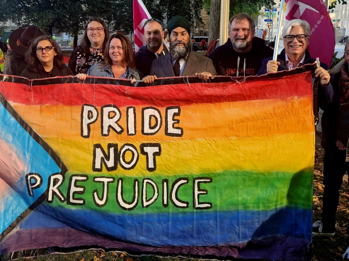 NDP leader Jagmeet Singh stands in the centre alongside union leaders holding a large Pride flag.